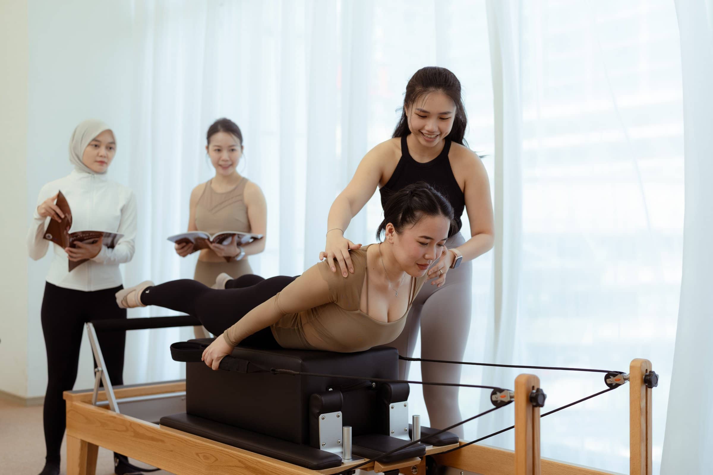 Pilates instructor assisting a student during training